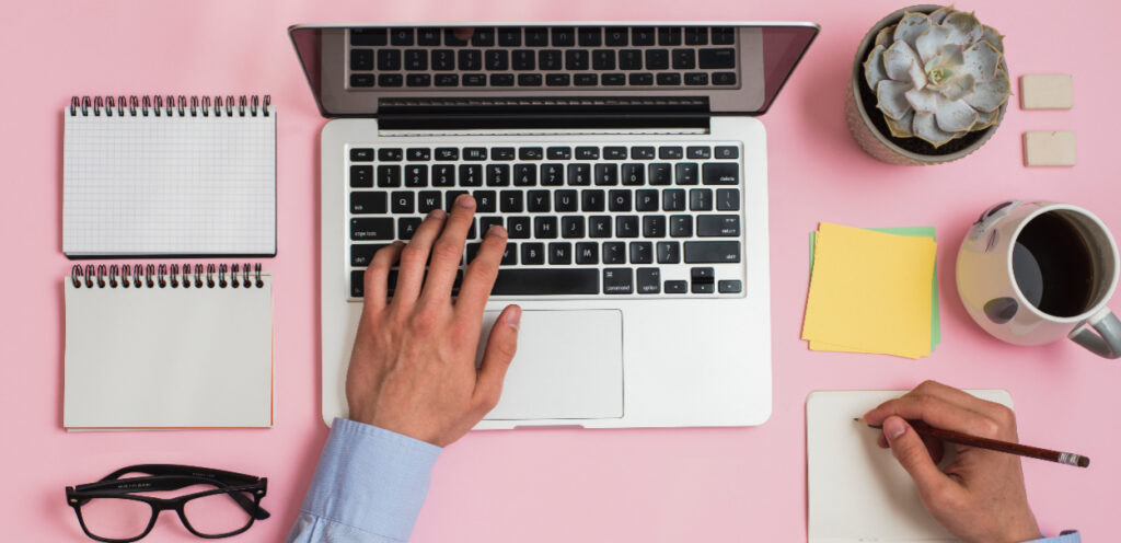 Mão em cima de teclado digitando, com outros objetos na mesa, simbolizando o programa de benefícios