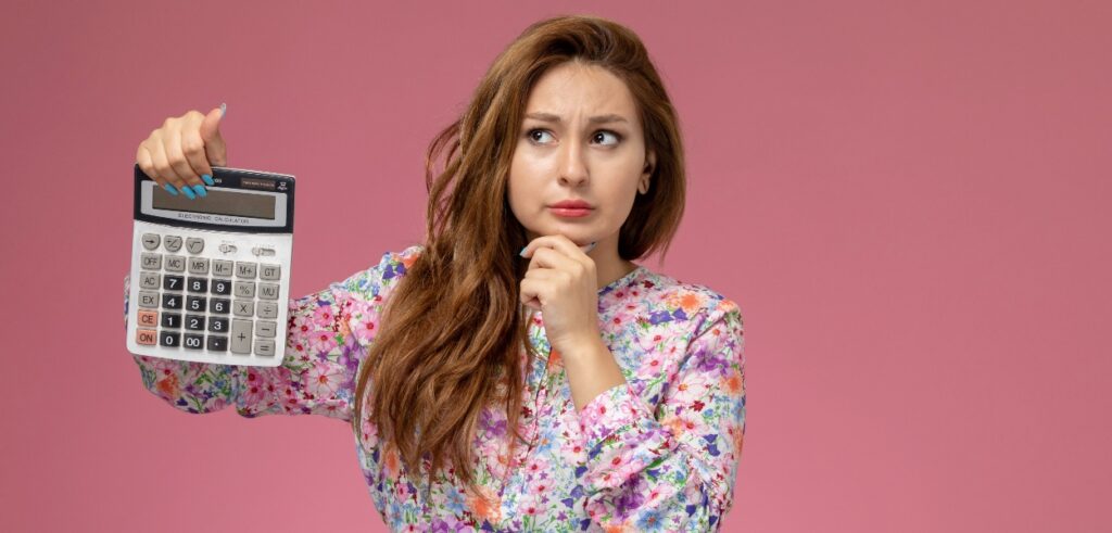 Mulher jovem segurando uma calculadora representando uma dúvida comum entre os colaboradores de uma empresa: como reduzir o estresse financeiro?