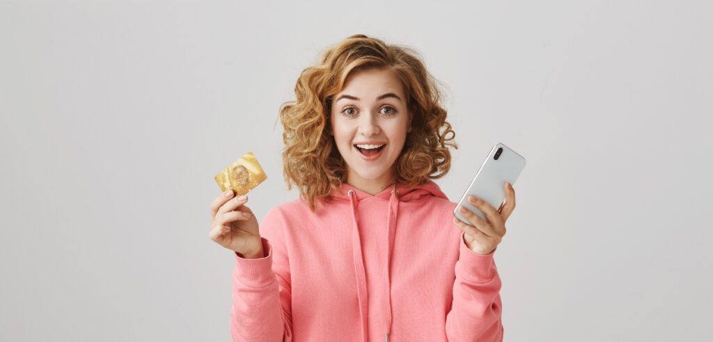 Mulher feliz com dinheiro e celular na mão para representar os benefícios flexíveis Allya.