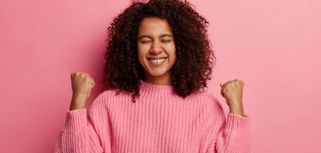 Mulher feliz comemorando que sua empresa se preocupa com o bem-estar da mulher.