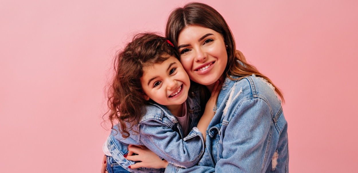 Foto de uma mãe com sua filha em um fundo rosa, representando como motivas as empresas no Dia das Mães