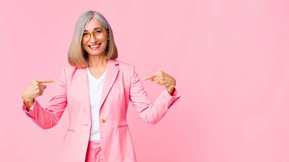 Mulher de blazer rosa apontando para si mesma destacando pacote de benefícios.