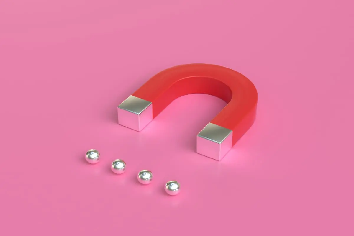 Imã vermelho em fundo rosa significando a atração e retenção de talentos na empresa