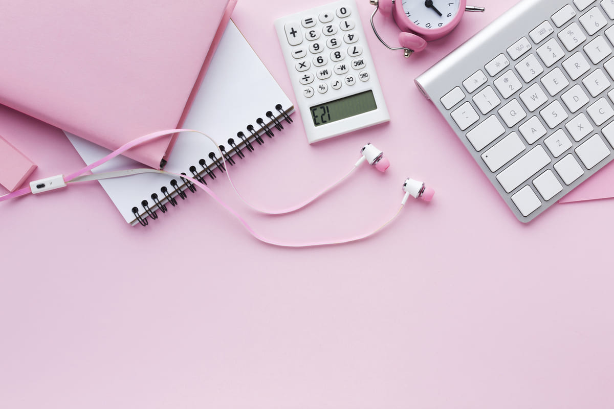 Mesa de trabalho rosa com teclado, calculadora e caderno para processos de RH.